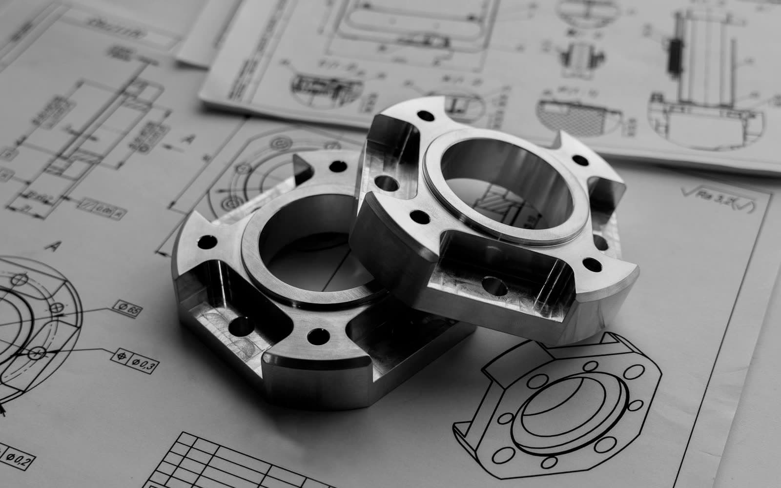 Machined metal parts resting on engineering drawings