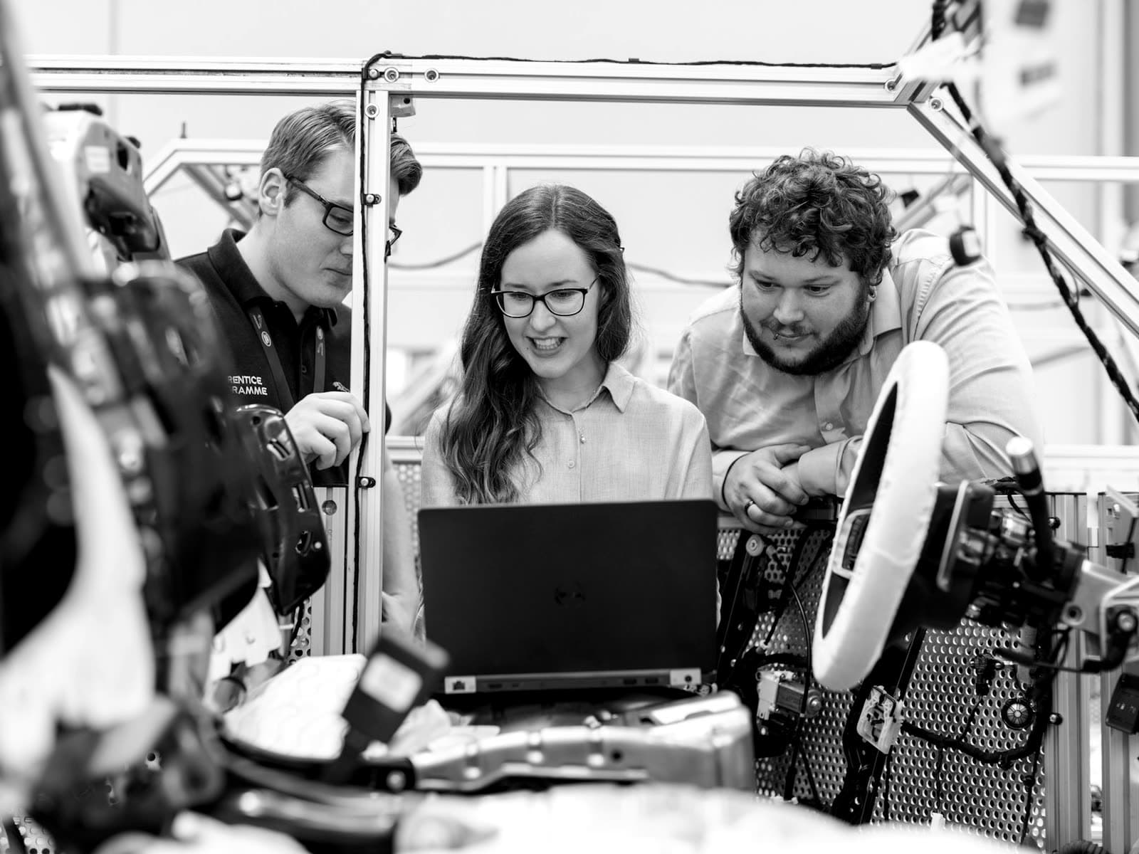 Engineering team reviewing a laptop on the production floor